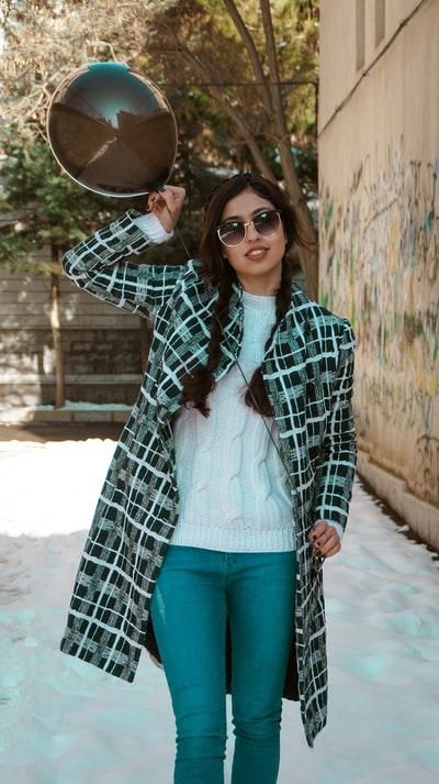 Dressed in a black and white plaid coat and blue denim jeans, wearing a brown hat lady
